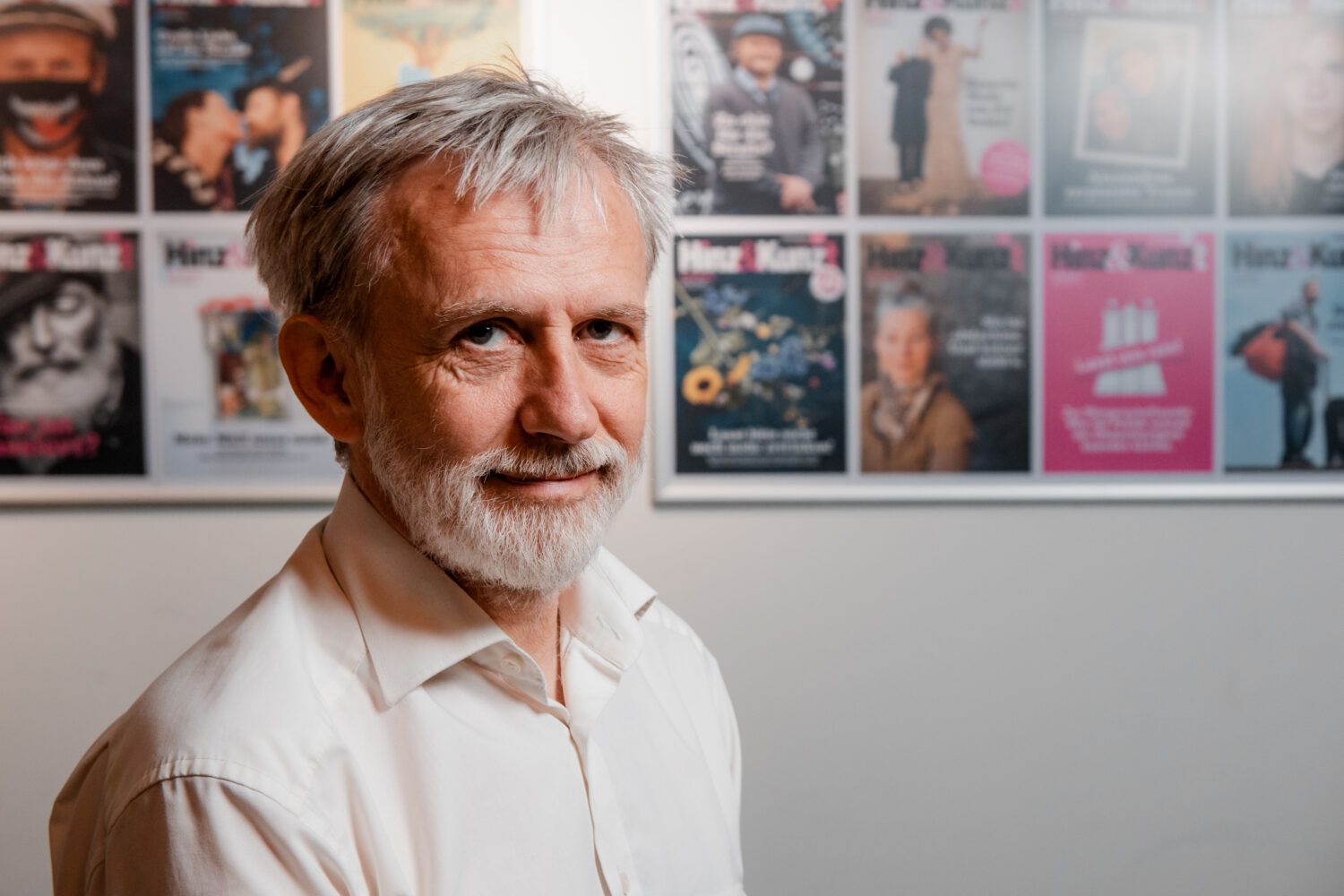 Ein Mann steht vor einer Wand mit den Titelseiten des Magazins Hinz&Kunzt.