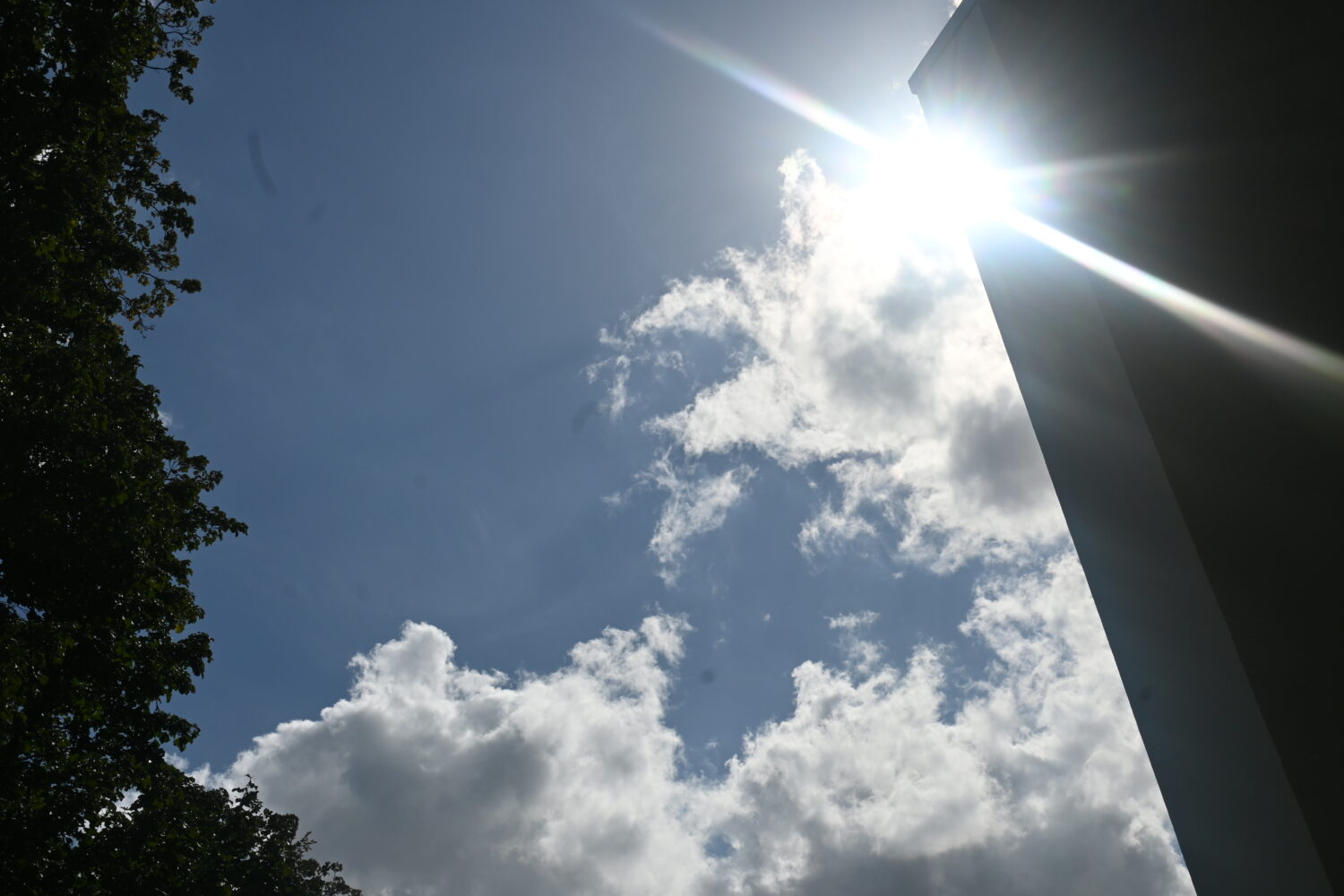 Ein Foto vom Himmel, bei dem die Sonne um die Ecke eines Hauses scheint.