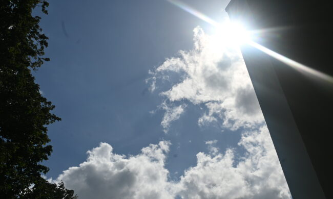 Ein Foto vom Himmel, bei dem die Sonne um die Ecke eines Hauses scheint.