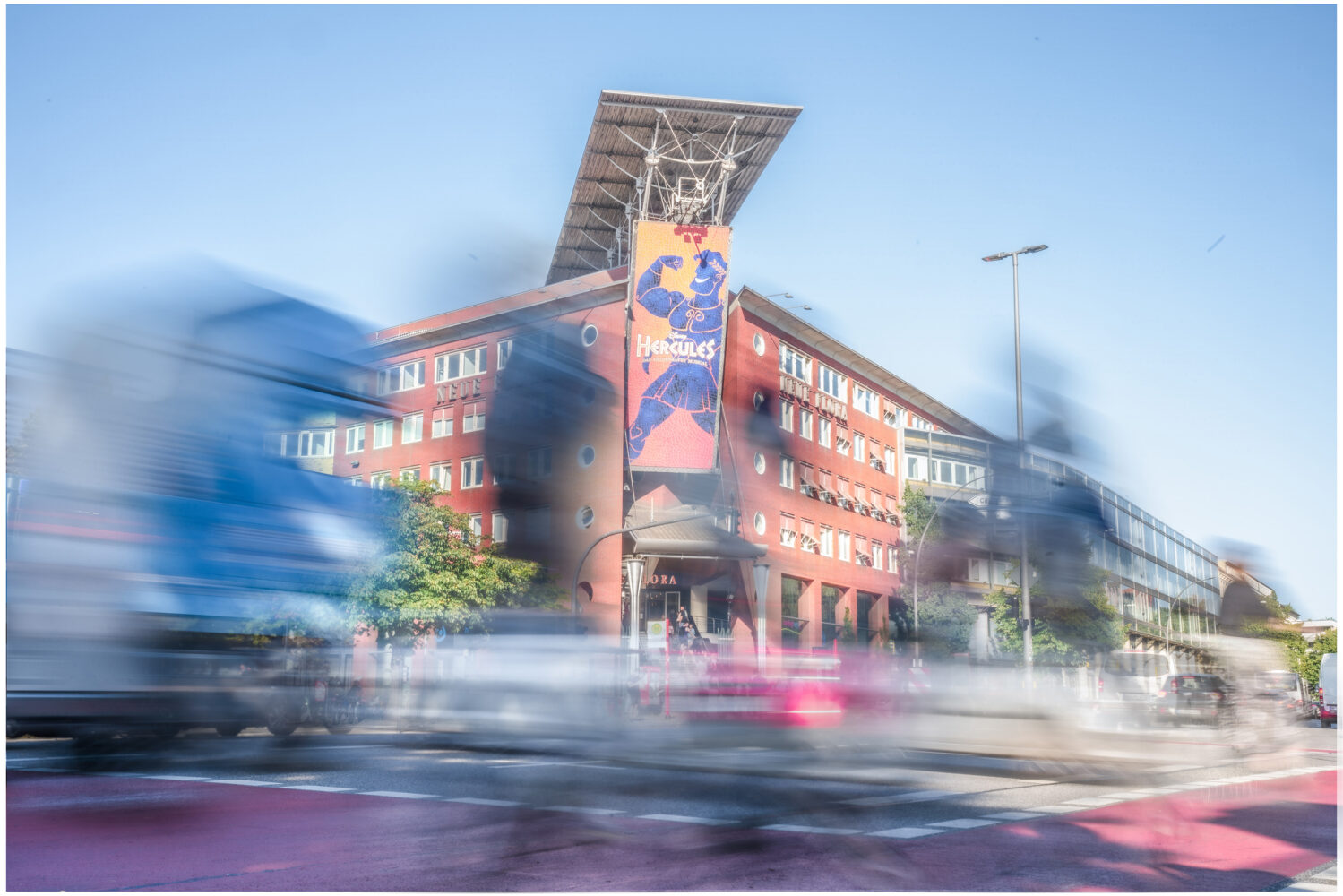 Ein Bild von der Neuen Flora in Altona, währenddessen vor dem Gebäude reger Verkehr herrscht.