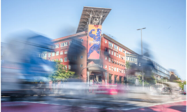 Ein Bild von der Neuen Flora in Altona, währenddessen vor dem Gebäude reger Verkehr herrscht.