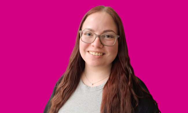 Junge Frau mit Brille lächelt in die Kamera.