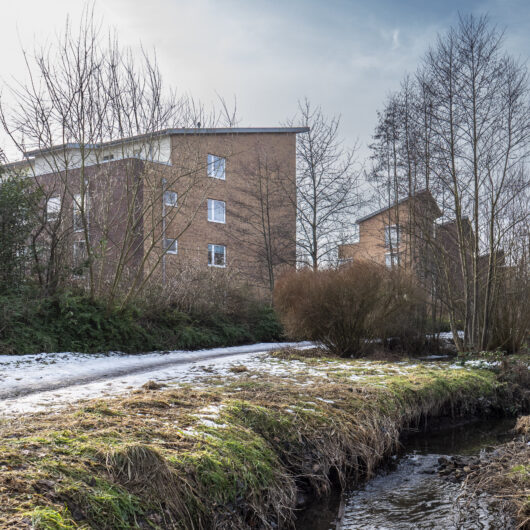 Bach und Mehrfamilienhaus.