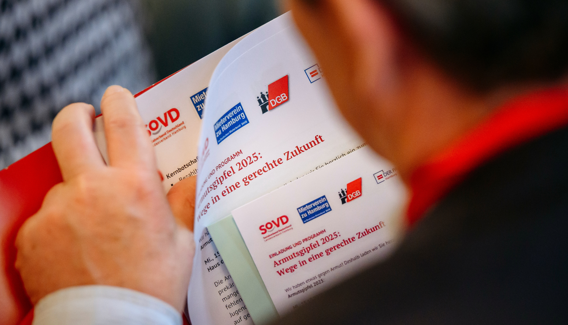 Blick über die Schulter eines Mannes auf ein Programmheft.