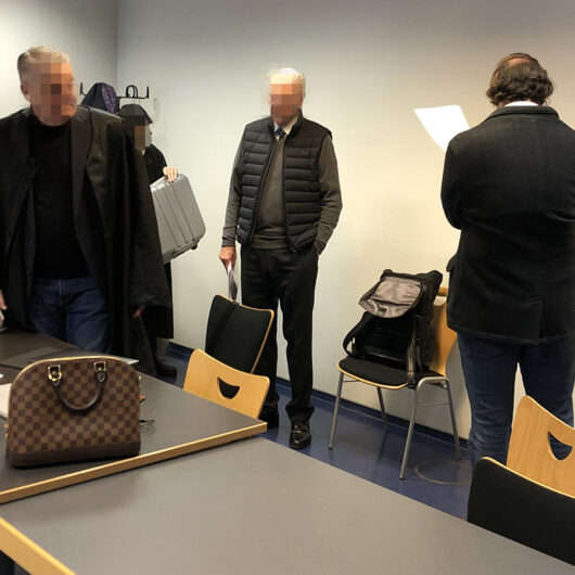 Szene in einem Gericht, drei Personen zu sehen, die Gesichter sind unkenntlich gemacht.