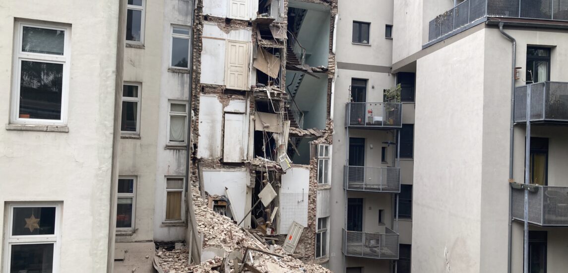 Halb abgerissenes Haus zwischen anderen Altbauten.