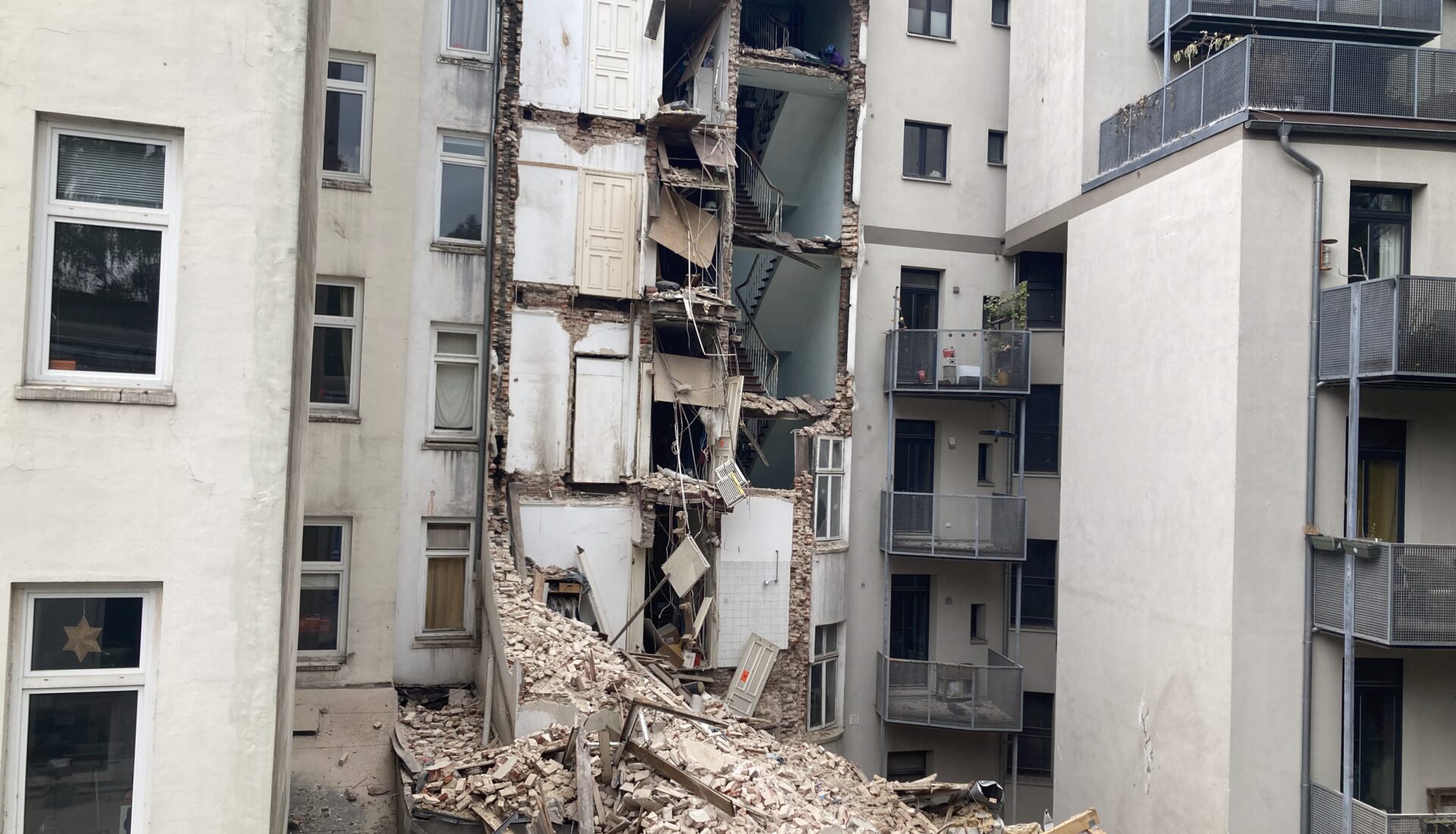 Halb abgerissenes Haus zwischen anderen Altbauten.