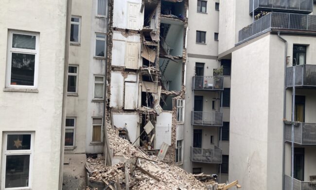 Halb abgerissenes Haus zwischen anderen Altbauten.