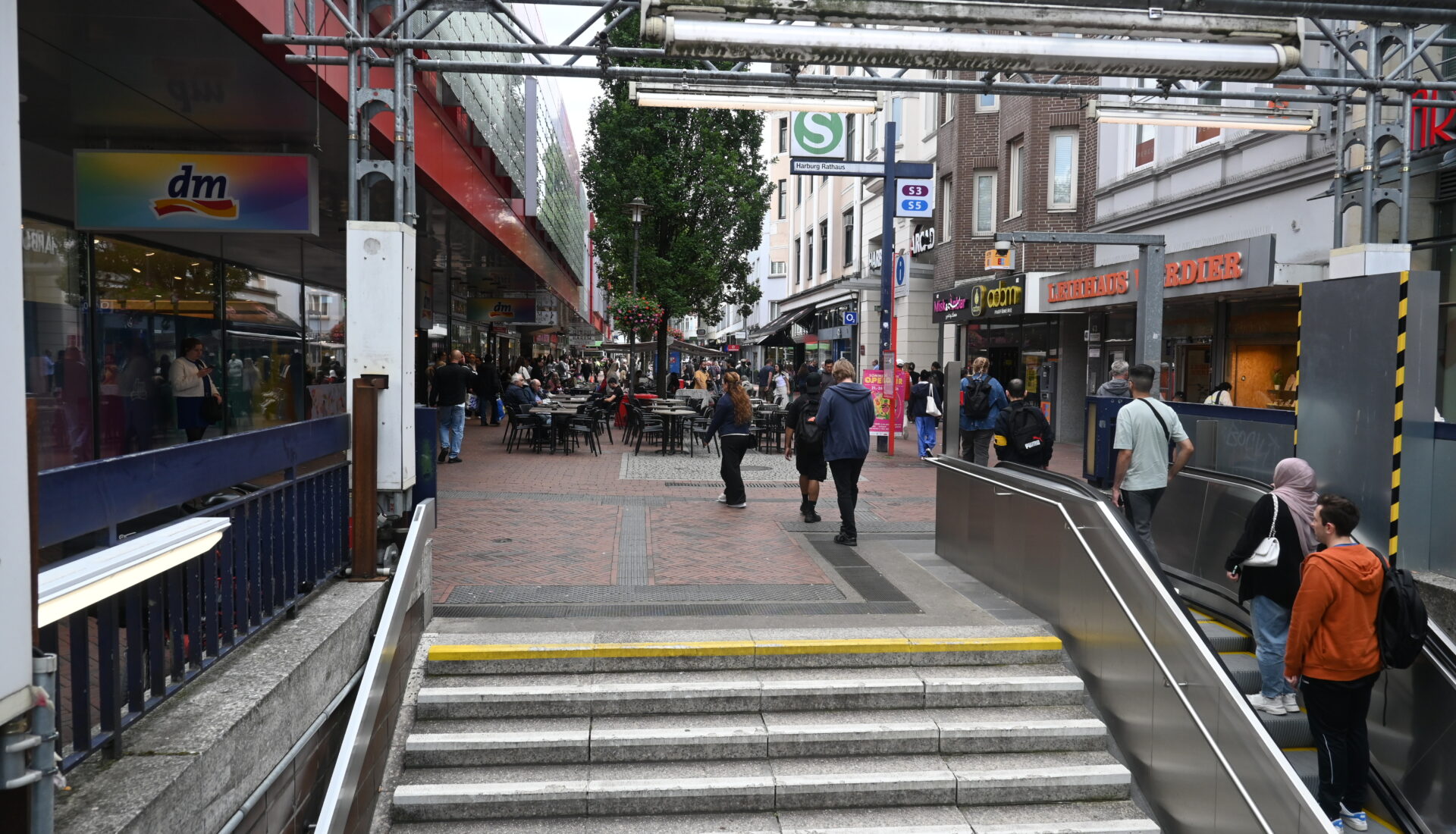 Rolltreppe und Blick in eine Einkaufsstraße mit Fußgängerzone.