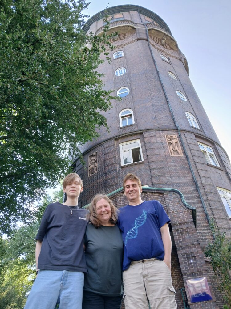 Drei Menschen stehen vor einem Wasserturm.