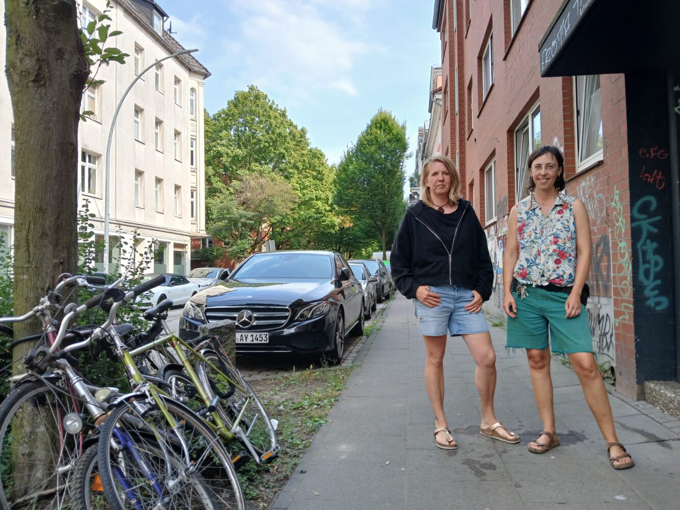 Zwei Frauen stehen auf einem Fußgängerweg.