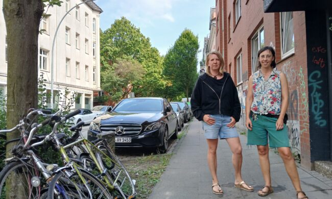 Zwei Frauen stehen auf einem Fußgängerweg.